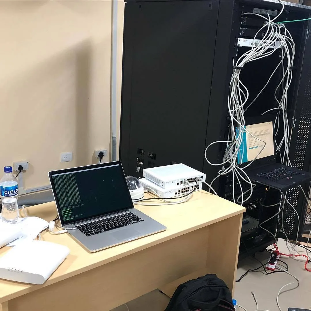 An aBit laptop running network configuration on a desk beside a client equipment rack
