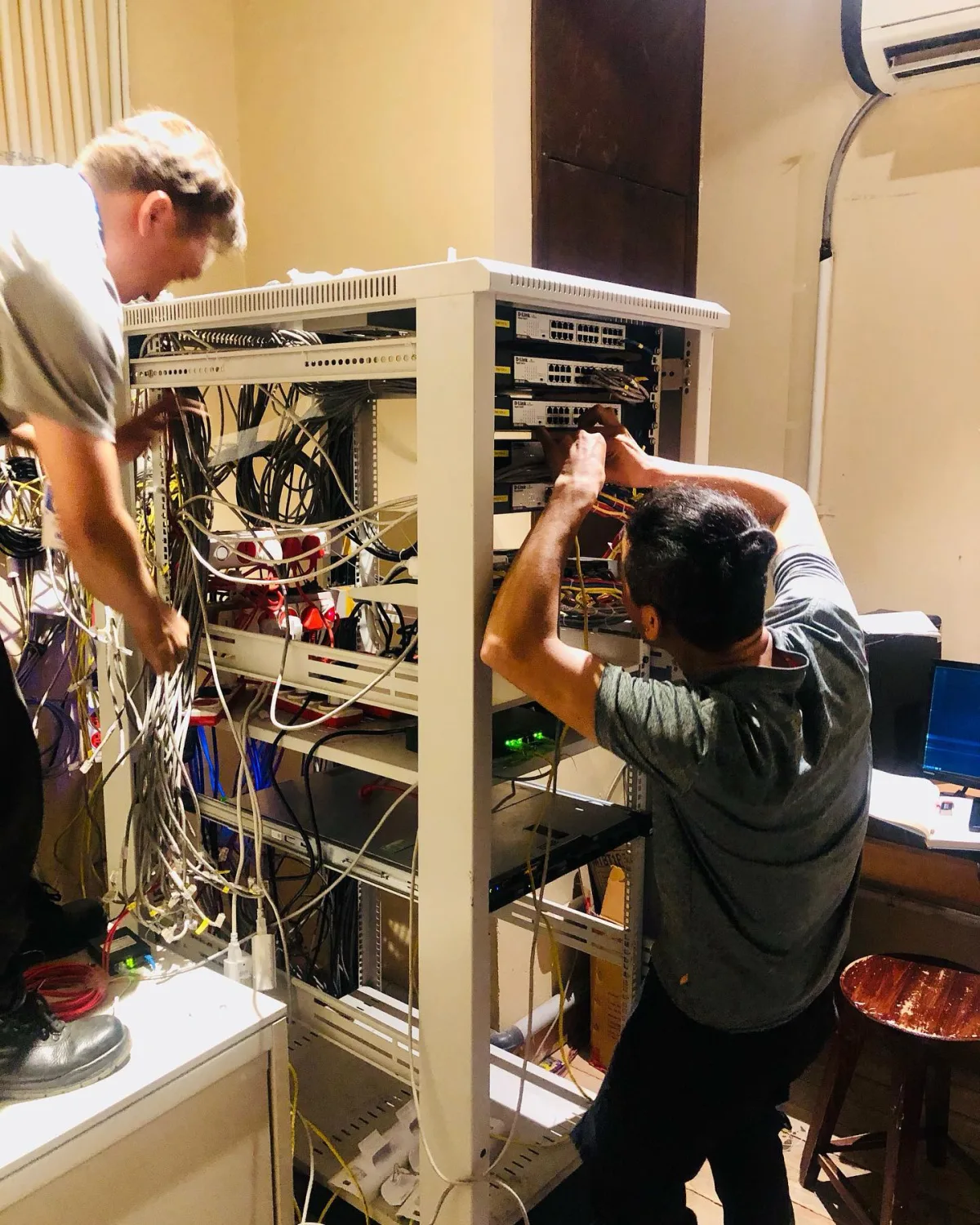 Two aBit engineers installing switches and dressing cabling in an open equipment rack at a client site