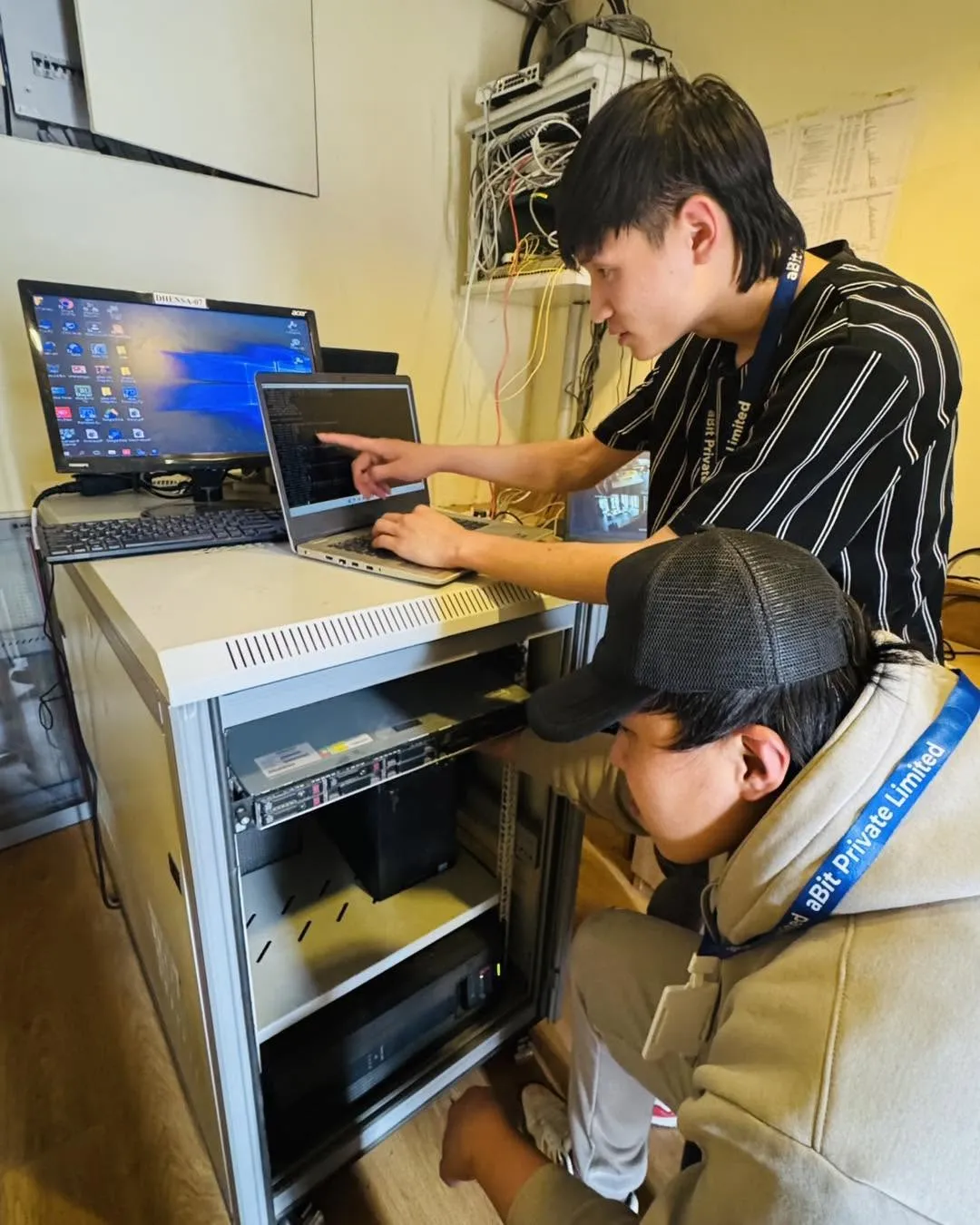 Two aBit engineers configuring a rack-mounted server from a laptop at a client site