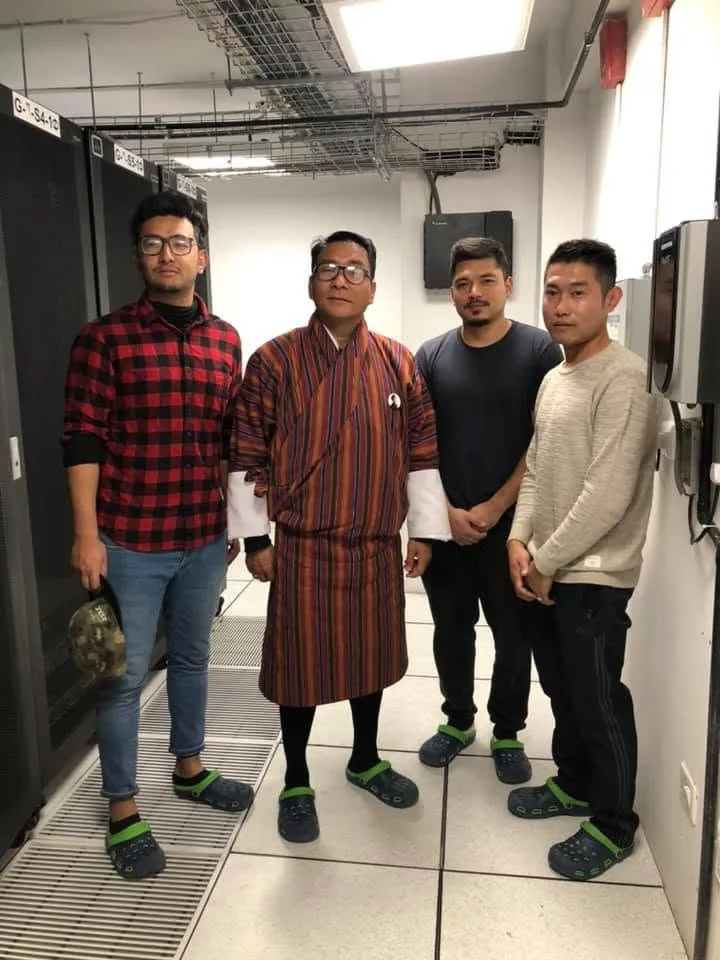 Four members of the aBit team standing in the aisle of a live data centre between rows of server racks
