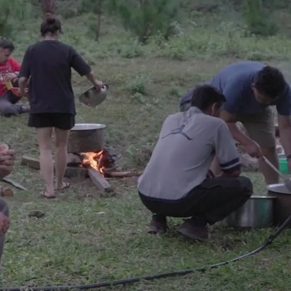 Cooking together over an open fire at a camp