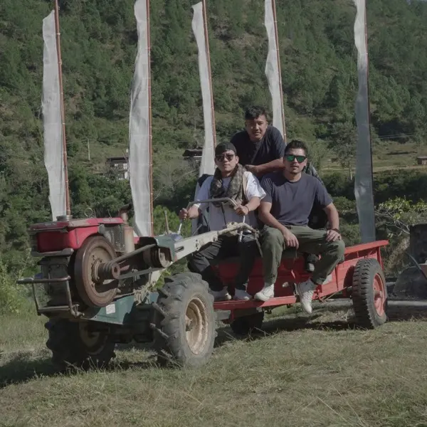 Three of the team on a power tiller beside prayer flags