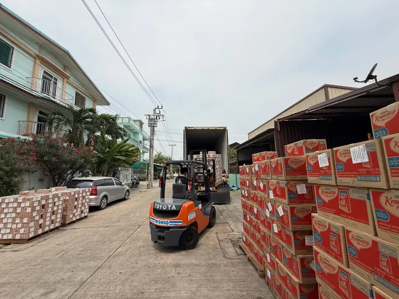 A forklift working between lanes of palletised cartons during container loading at the Bangkok warehouse